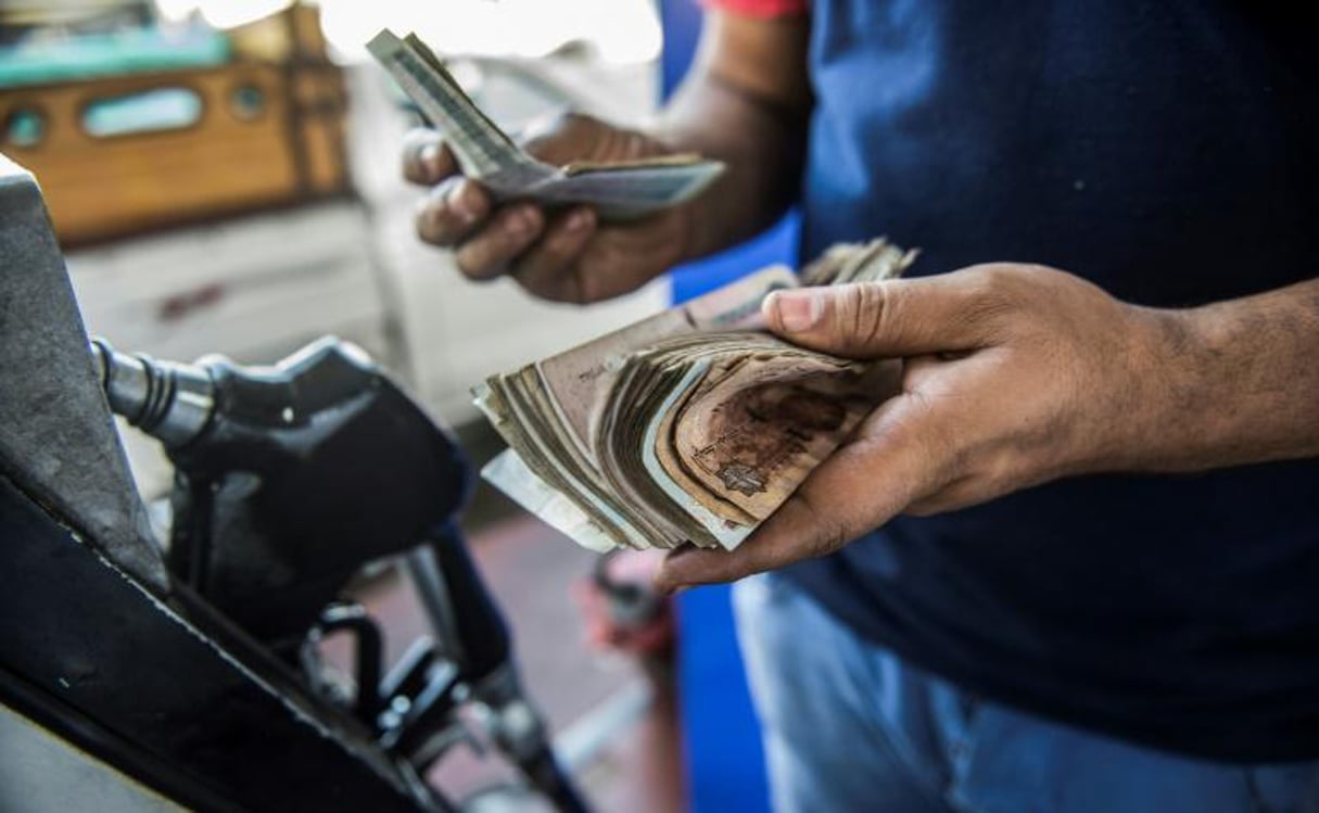 Un employé d’une station-service compte l’argent qu’il vient de recevoir d’un client, le 29 juin 2017 au Caire, en Égypte. © Khaled Desouki/AFP