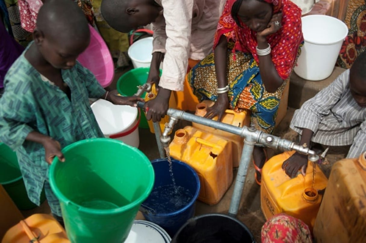 Des femmes et des enfants du camp de déplacés de Muna, à la périphérie de la grande ville de Maiduguri, capitale de l’État du Borno, au Nigeria, collectent de l’eau d’un puits le 30 juin 2016. © Stefan Heunis/AFP