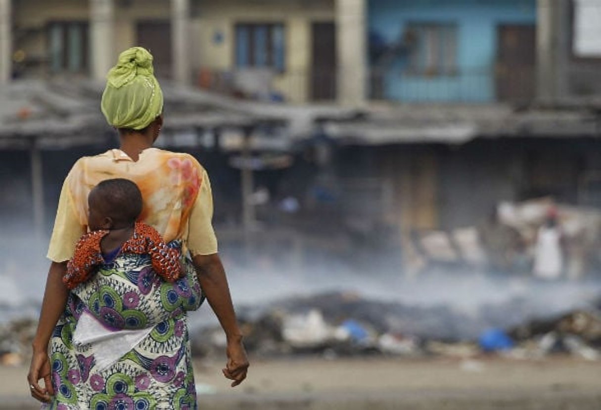 Une femme observe les décombres fumantes au marché d’Abobo, pendant la crise postélectorale, le 4 mars 2011. © Rebecca Blackwell/AP/SIPA