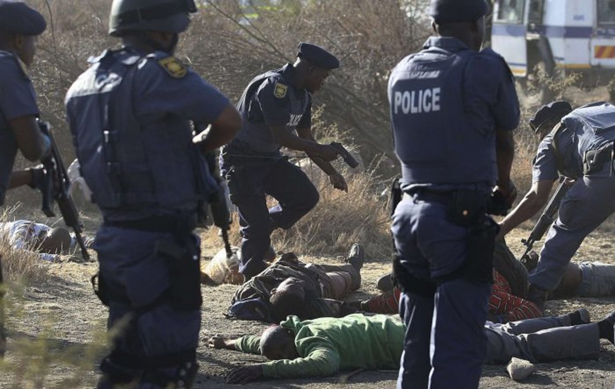 Des policiers sud-africains se tiennent près des corps de mineurs tombés à Marikana, le 16 août 2012. © AP/SIPA