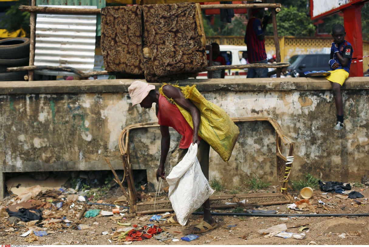 Un homme ramassant des ordures en plastique au port de pêche de Conakry, en Guinée, mardi 25 novembre 2014. © Jerome Delay/AP/SIPA