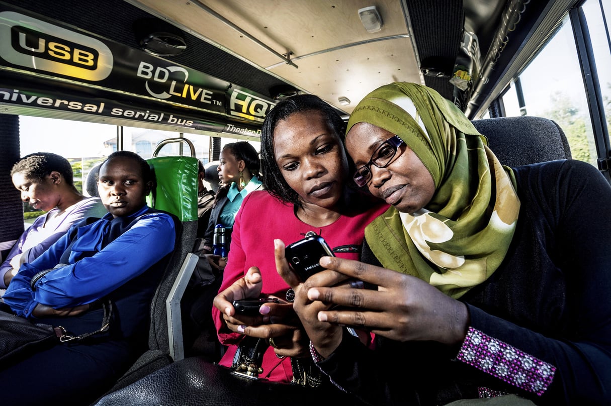 Nairobians using the internet on their smart phones as they ride on a city bus. Kenya’s biggest telecoms company, Safaricom, has begun installing wifi in matatus, the packed minibuses and vans that ply the city providing residents of the capital the cheapest form of urban travel. The wifi is free to passengers but the matatu drivers pay a fee of about USD 25 a month for the router. However, those who have it installed say the free wifi has increased passenger numbers.  africa technology internet transport veiled women people © Sven Torfinn/PANOS-REA