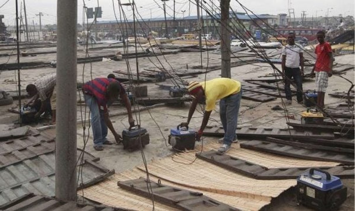 Des ouvriers réparant des générateurs sur les toits d’un marché de Lagos, au Nigeria, en 2010. © Sunday Alamba/AP/SIPA