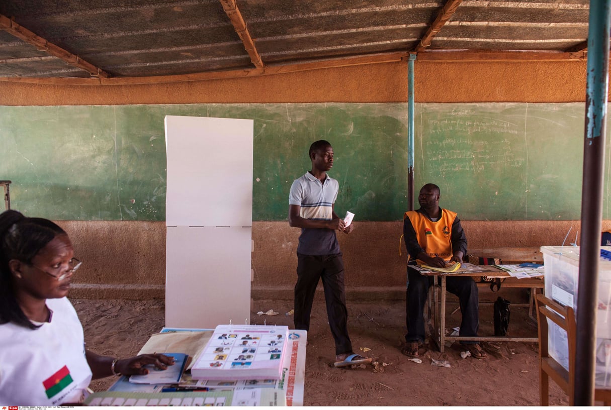 Un électeur burkinabè (au centre) avançant avec son bulletin de vote pour le déposer dans l’urne lors du scrutin 29 novembre 2015 à Ouagadougou. © Theo Renaut/AP/SIPA