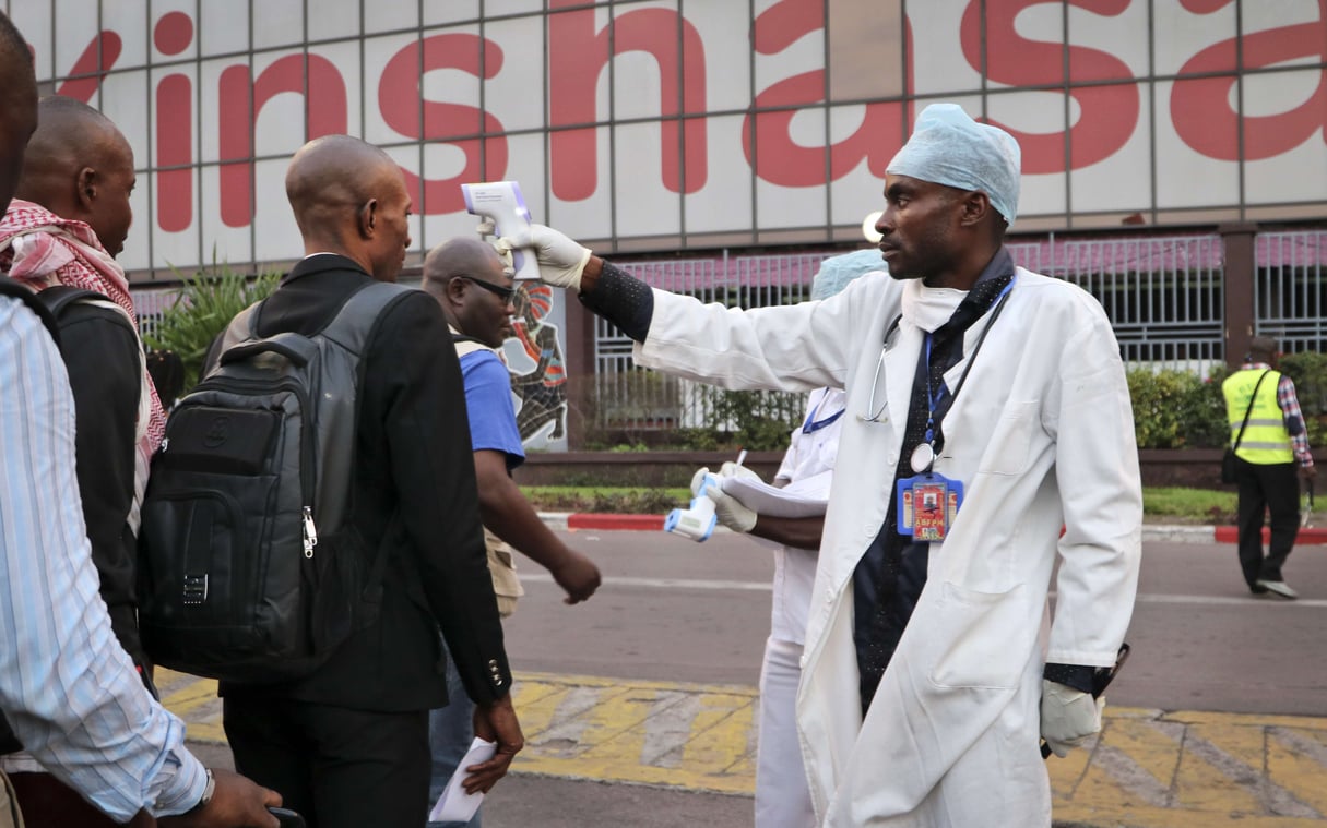 Un agent de santé vérifie, le 2 juin 2018, la température des personnes qui descendent d'un avion à l'aéroport de Kinshasa, en RDC.. &copy; Sam Mednick/AP/SIPA