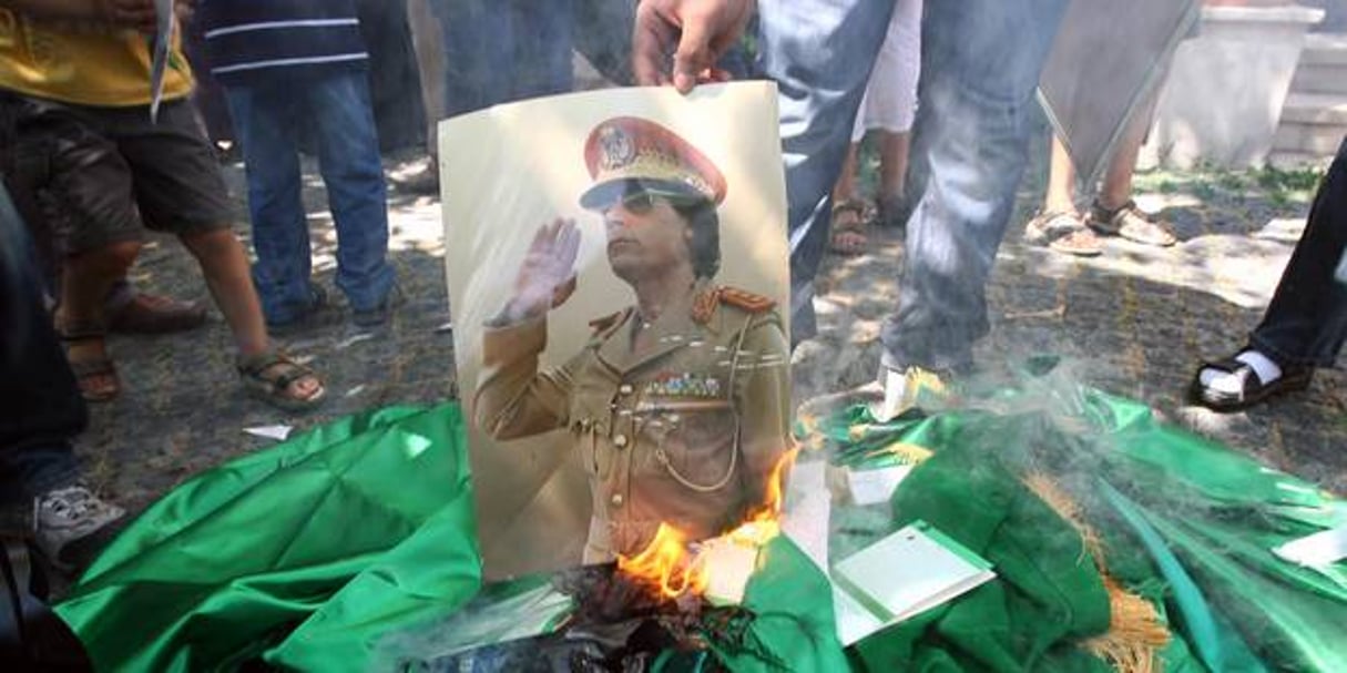 Une photo de Mouammar Kadhafi brûlée lors d’une manifestation d’opposants en 2011. © AFP