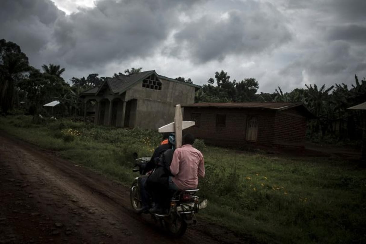 Des Congolais portent une croix destinée à un cimetière sur la route entre Mangina et Beni, le 23 août 2018, dans le nord-est de la RDC. © AFP / John WESSELS