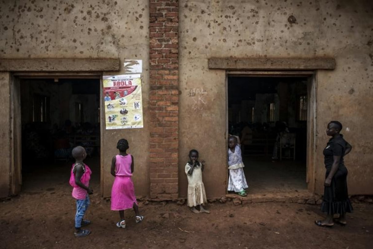 Des enfants en République démocratique du Congo regardent une affiche expliquant les symptômes d’Ebola, à Mangina, le 19 août 2018. © John WESSELS / AFP