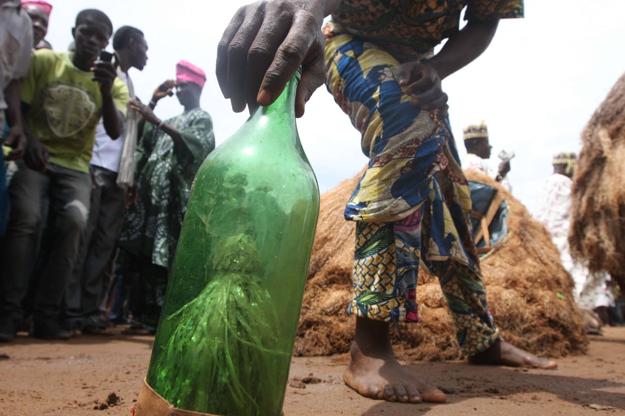 Un homme s'apprête à ramasser une bouteille contenant le "juju", une magie noire qui aide à danser avant une cérémonie à Ijoko, au Nigeria, en 2012. &copy; Jon Gambrell/AP/SIPA