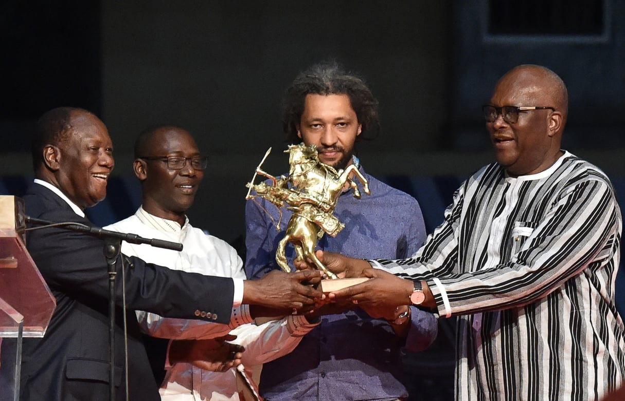 Alain Gomis reçoit le trophée des mains de Roch Marc Christian Kabore et d’Alassane Ouattara, en 2017. © ISSOUF SANOGO / AFP