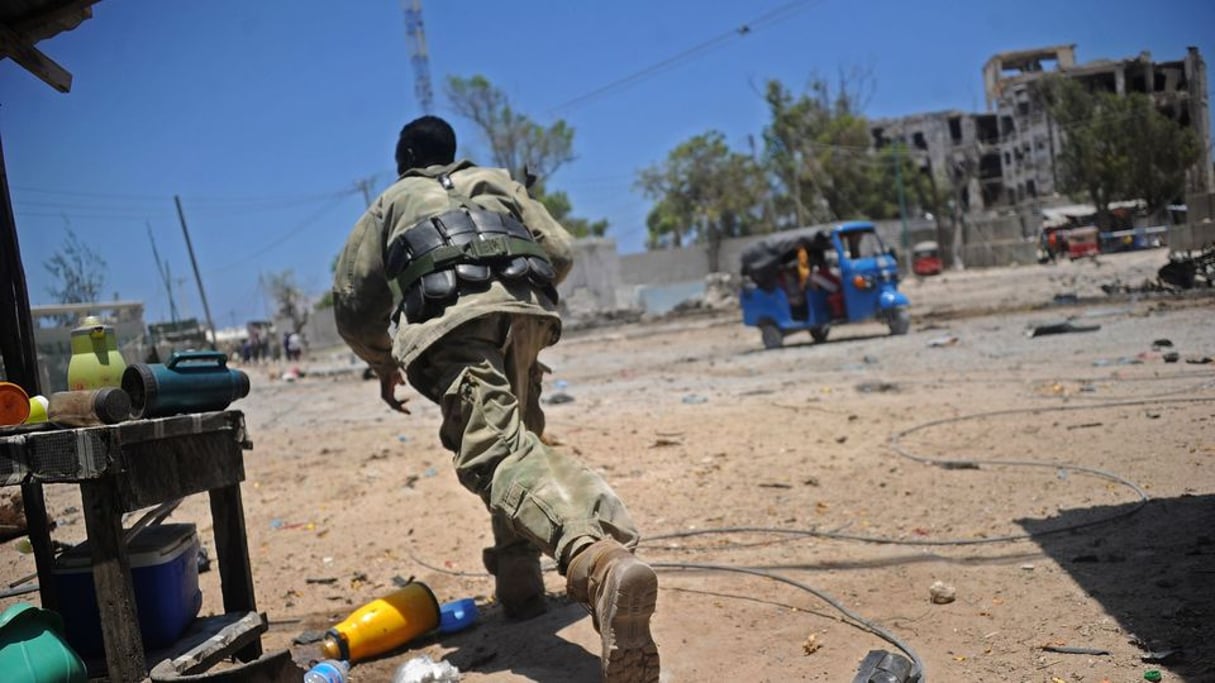 Un soldat somalien se met à l’abri pendant l’attaque de ministères par les islamistes shebab, le 23 mars 2019 à Mogadiscio. © AFP / MOHAMED ABDIWAHAB