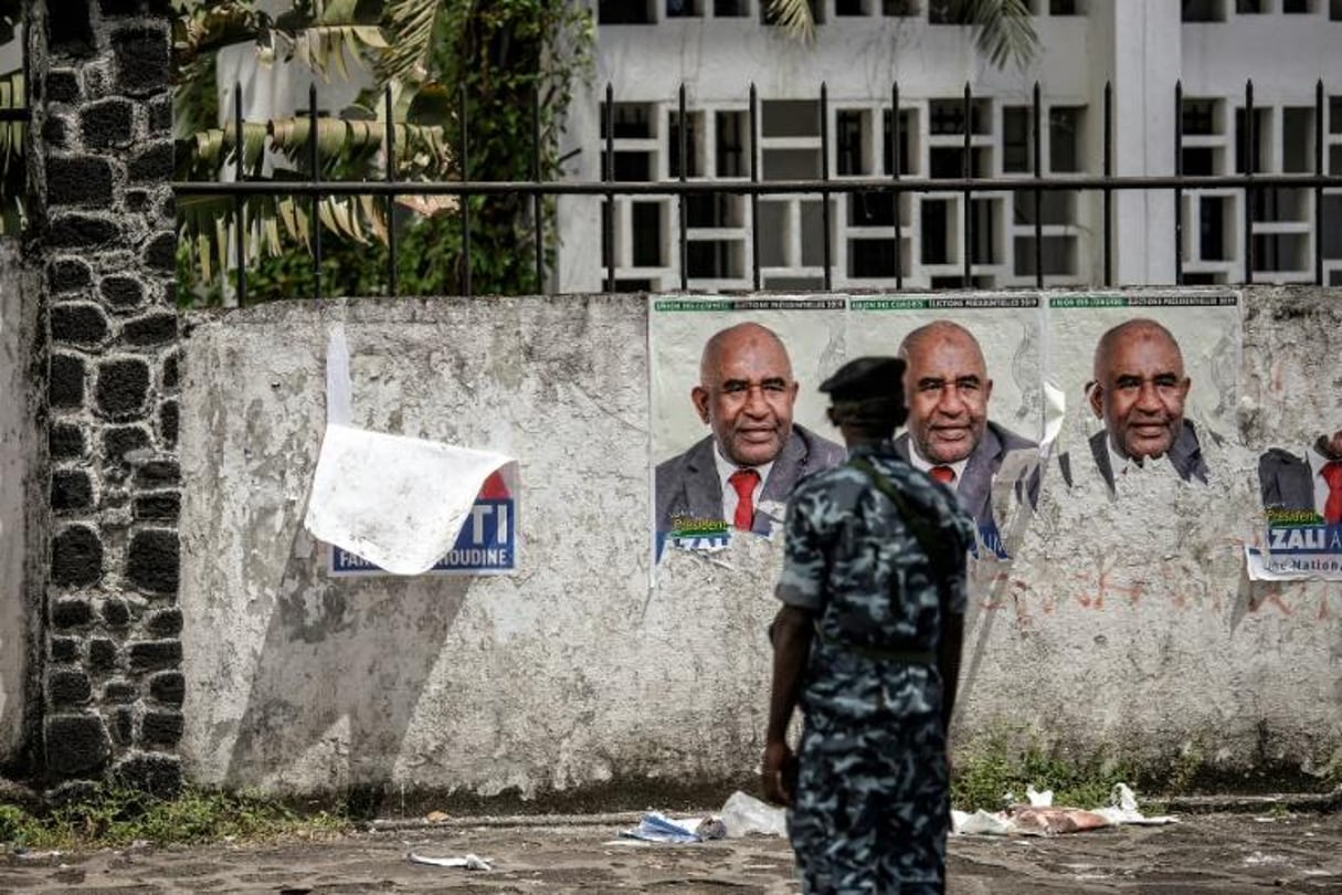 Un policier devant des affiches électorales du président sortant, Azali Assoumani, le 25 mars 2019 à Moroni, aux Comores. © GIANLUIGI GUERCIA / AFP