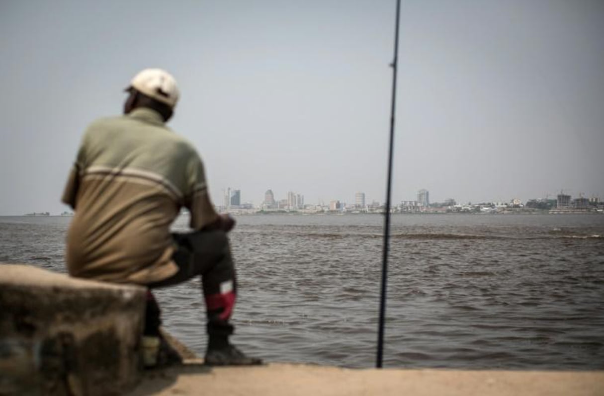 Un homme pêche sur la rive du fleuve Congo, à Brazzaville, (République du Congo) le 22 juillet 2015, avec vue, de l’autre côté du fleuve, sur Kinshasa, en RDC. © FEDERICO SCOPPA/AFP