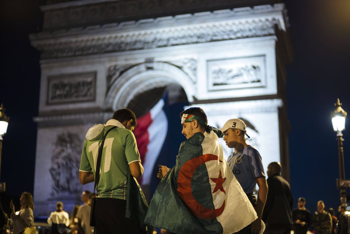 Des supporteurs de football arborant le drapeau algérien devant l’Arc de Triomphe, à Paris, dimanche 14 juillet après la victoire des Fennecs en demi-finale de la CAN. © Kamil Zihnioglu/AP/SIPA