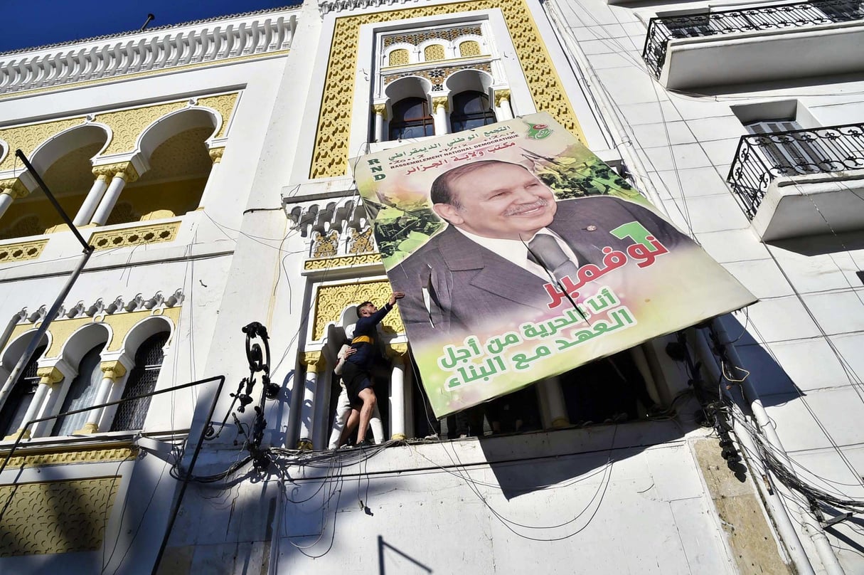 Des manifestants décrochant un portrait du président Bouteflika,le 22 février 2019, à Alger. © RYAD KRAMDI/AFP