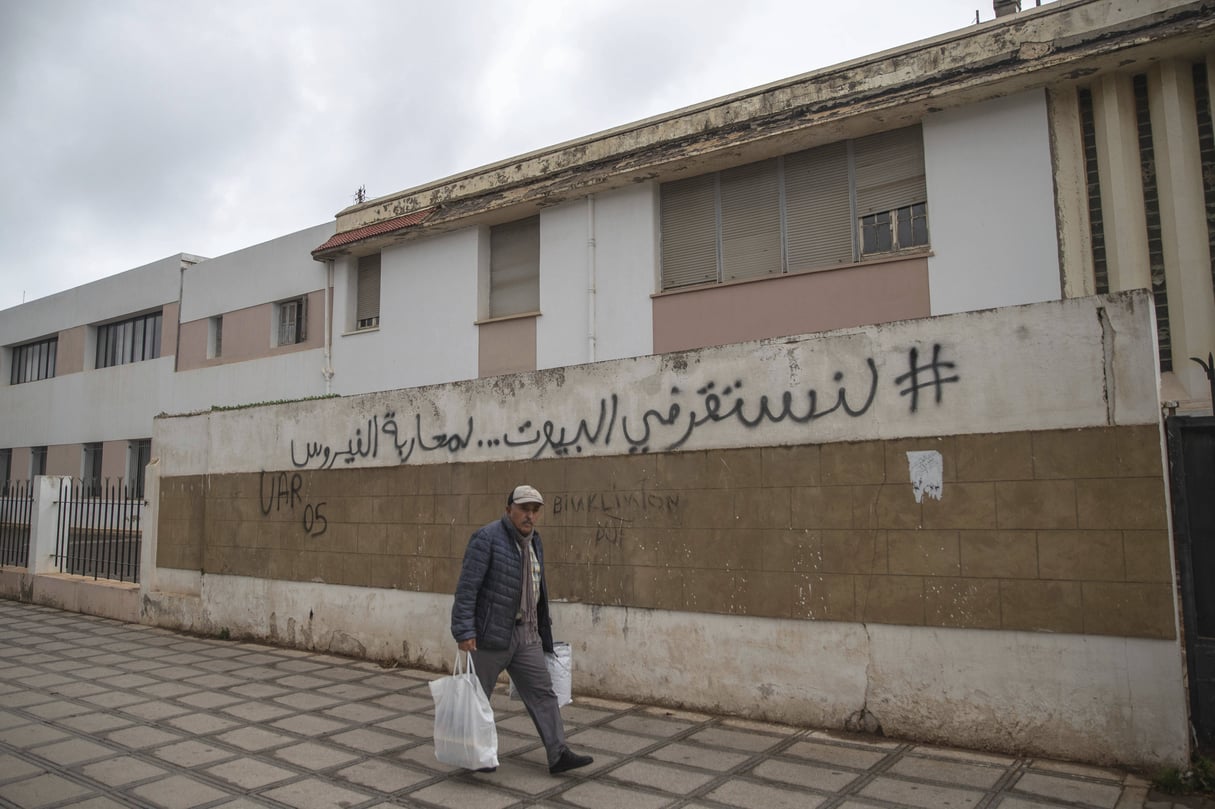 Un homme passe devant une écriture murale qui encourage les gens à rester à la maison pour empêcher la propagation du coronavirus, à Rabat, le 20 mars 2020. © AP/SIPA/Mosa’ab Elshamy