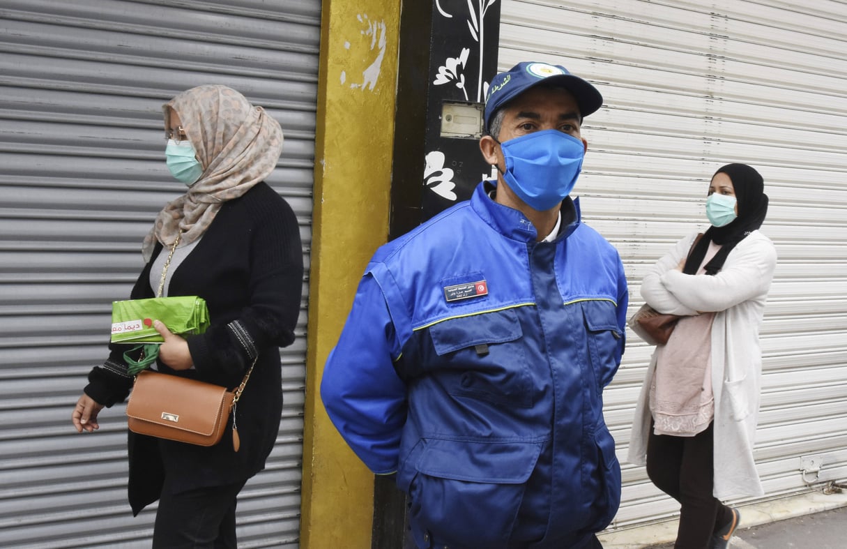 Un garde de sécurité se tient à côté de femmes portant des masques, gardant des distances sociales et faisant du shopping pour le ramadan, à Tunis, le 23 avril. © Hassene Dridi/AP/SIPA