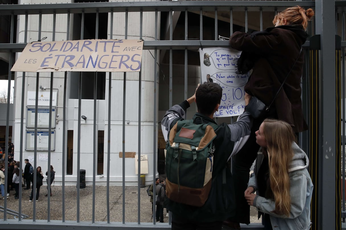 Des étudiants collent des affiches, dont l'une porte le titre "Solidarité avec les étrangers", sur la clôture de l'université fermée de Tolbiac à Paris, le 5 décembre 2018. &copy; Christophe Ena/AP/SIPA