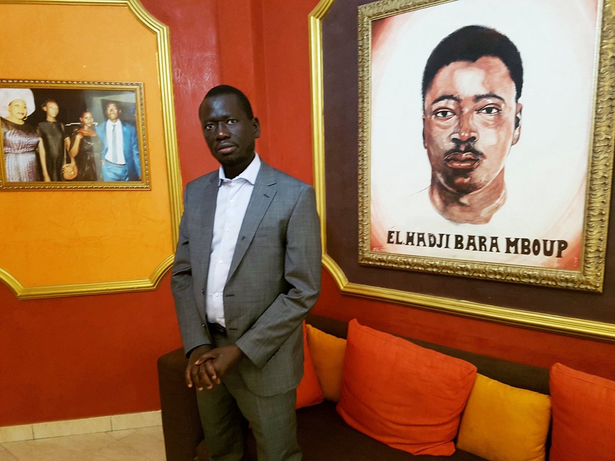 Serigne Mboup, devant le portrait de son père, fondateur du groupe CCBM, à Dakar le 20 février 2020. © Julien Clémençot pour JA