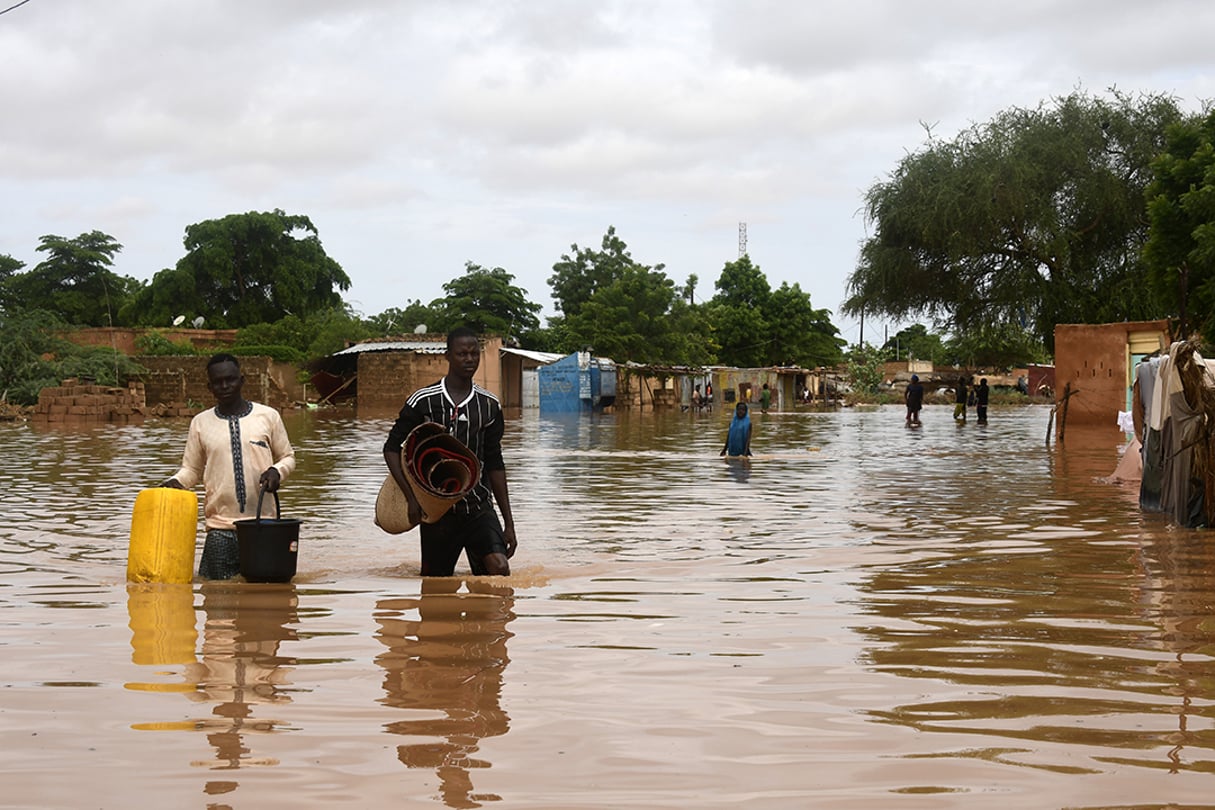 Des sinistrés de Kirkissoye, près de Niamey, victimes des inondations, le 27 août 2020. People carry their belongings while walking in a street flooded by the waters from the Niger river that flooded in the Kirkissoye neighbourhood in Niamey on August 27, 2020. 
© BOUREIMA HAMA / AFP