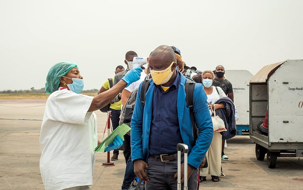 Un employé prend la température des passagers débarquant d’un vol d’Ethiopian Airlines à l’aéroport international N’Djili de Kinshasa le 15 août 2020. © Arsene Mpiana/AFP