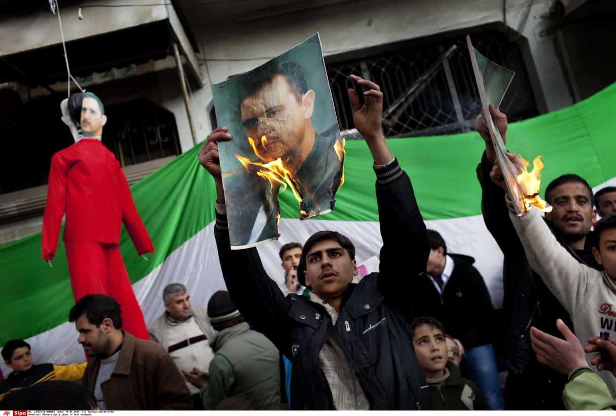 Des gens brûlent des portraits du président syrien Bachar Assad lors d’une manifestation contre son régime dans la banlieue d’Idlib, dans le nord de la Syrie, le 26 février 2012. © Rodrigo Abd/AP/SIPA