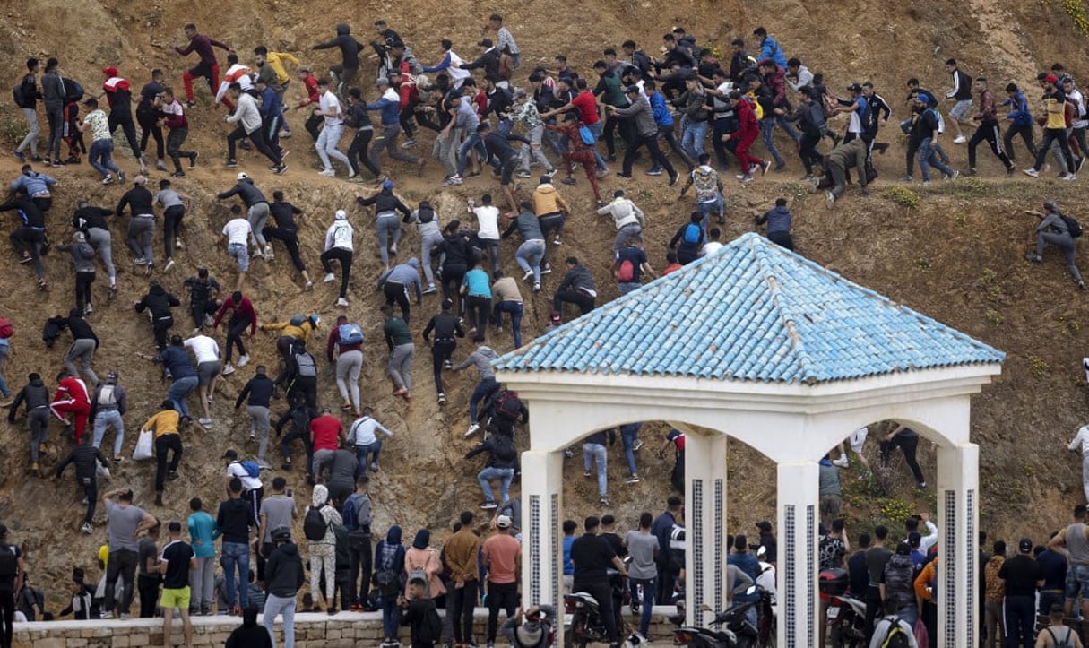 Des migrants évitent la police marocaine alors qu’ils tentent d’atteindre la frontière entre le Maroc et l’enclave espagnole de Ceuta, le 18 mai 2021 à Fnideq. © FADEL SENNA/AFP