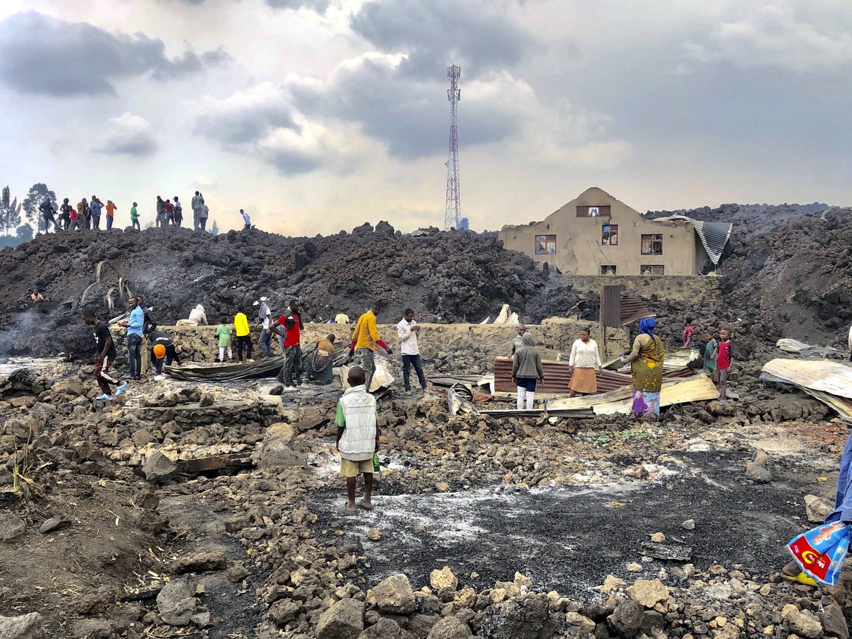 Des personnes se rassemblent sur une coulée de lave froide suite à l’éruption nocturne du Mont Nyiragongo à Goma, en RDC, le 23 mai 2021. © Clarice Butsapu/AP/SIPA