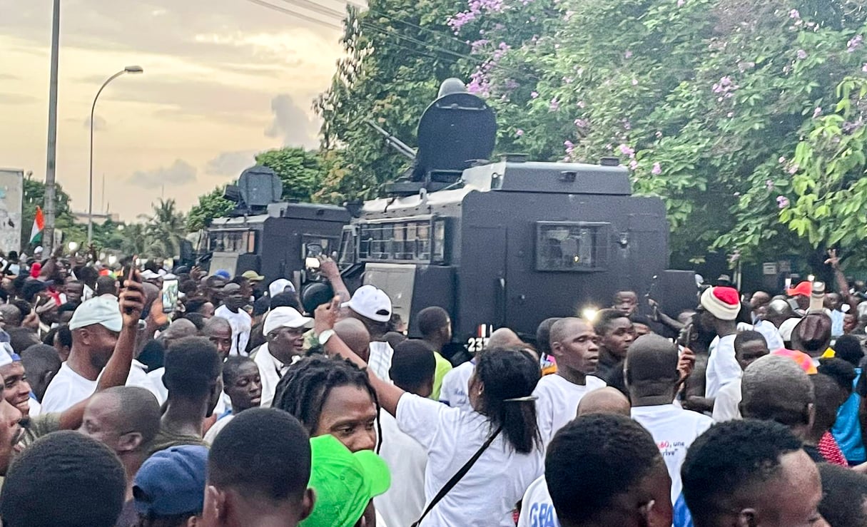 Des blindés des forces de l'ordre au milieu de la foule de partisans de Laurent Gbagbo, près du QG du FPI à Attoban, le 17 juin 2021, au moment de l'arrivée de l'ancien président ivoirien. &copy; Photo : Vincent Duhem pour JA