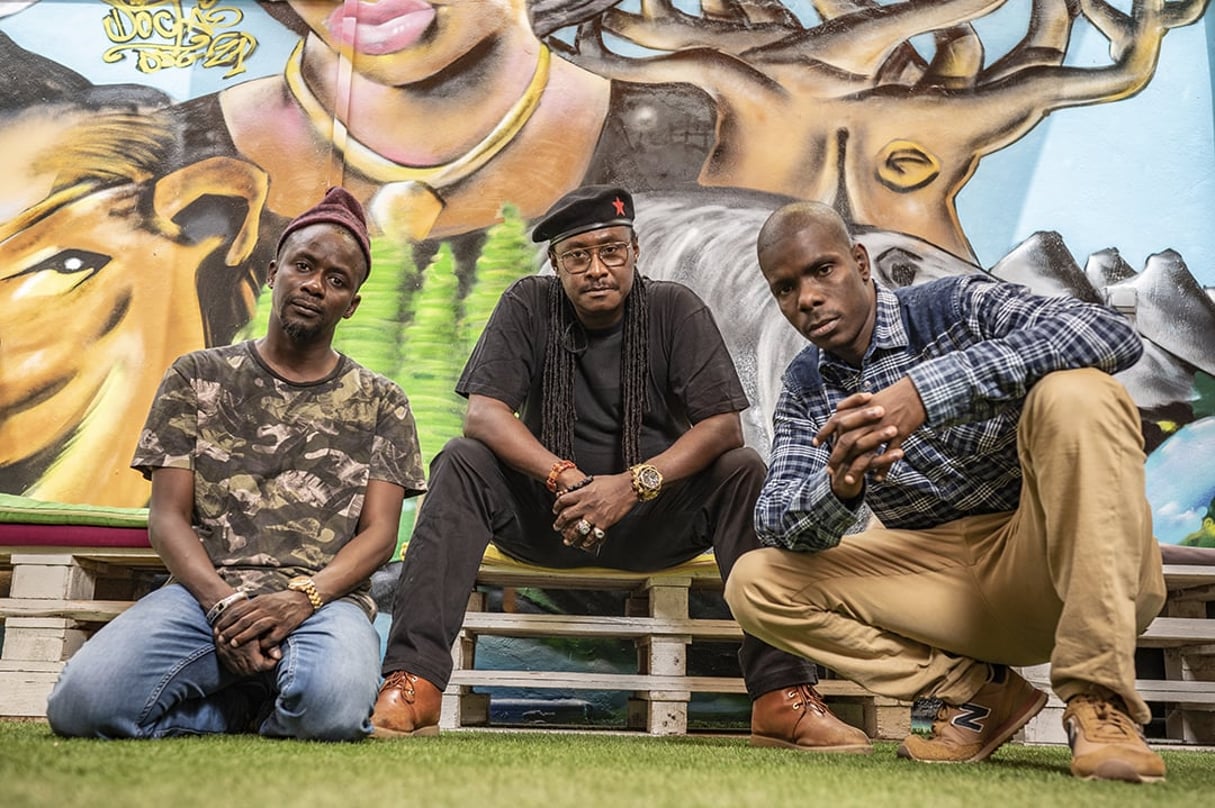 De g. à d., les rappeurs Fou Malade et Didier Awadi aux côtés d’Amadou Fall Ba, le 23 juin 2021, à la Maison des cultures urbaines de Dakar. © Sylvain Cherkaoui pour JA
