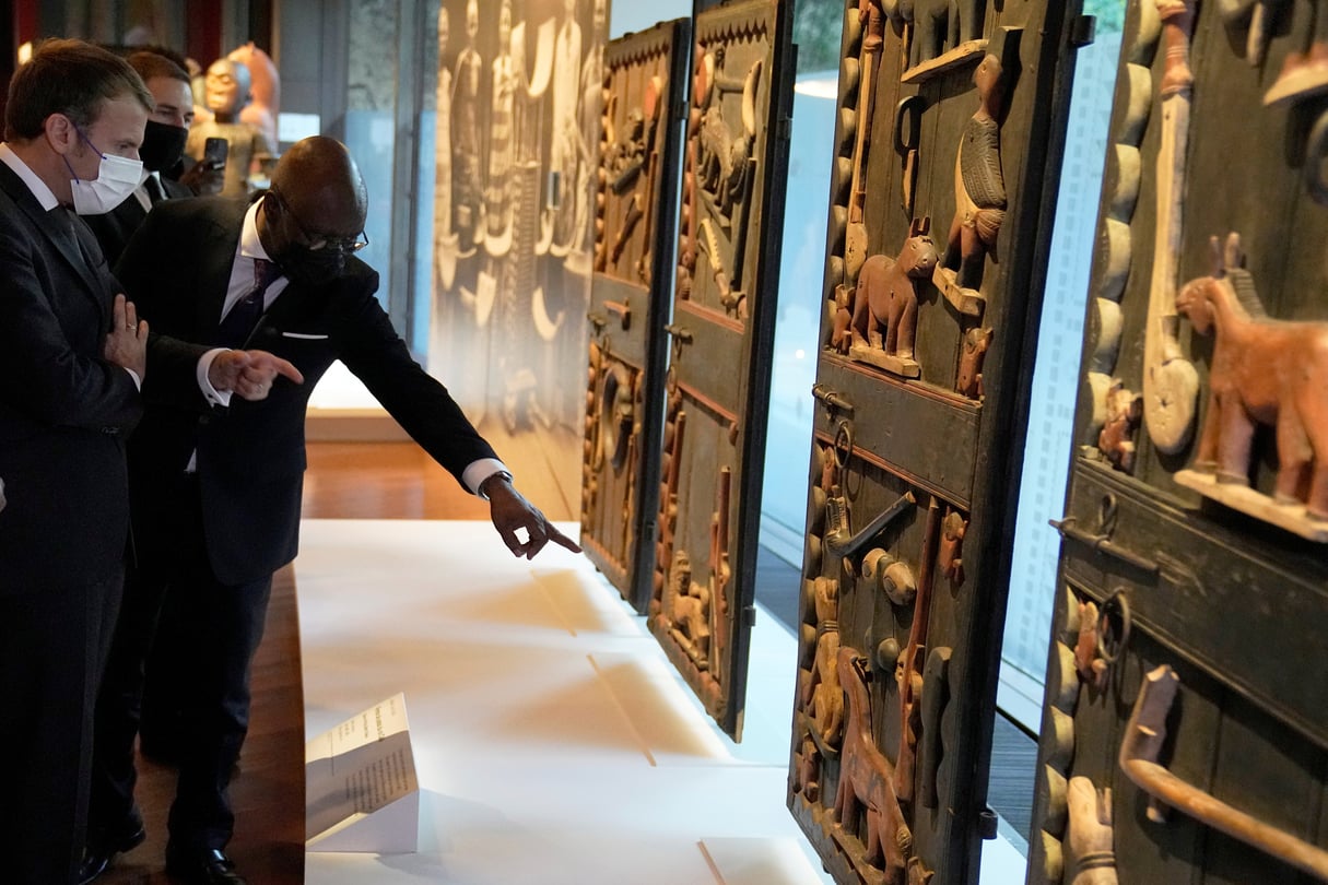 Le président français Emmanuel Macron et le ministre béninois des Affaires étrangères Aurélien Agbénonci, devant l’une des oeuvres qui sera restituée au Bénin, le 27 octobre 2021 au musée du quai Branly, à Paris. © Michel Euler/Pool via REUTERS