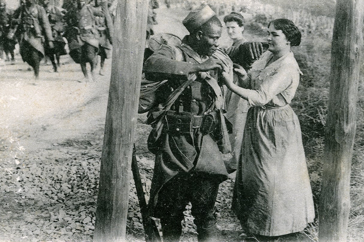 Dans la campagne française, en Champagne, une vendangeuse offre du raisin à un tirailleur sénégalais blessé (carte postale envoyée en 1914). © Gusman/Leemage (Photo by leemage / Leemage via AFP)