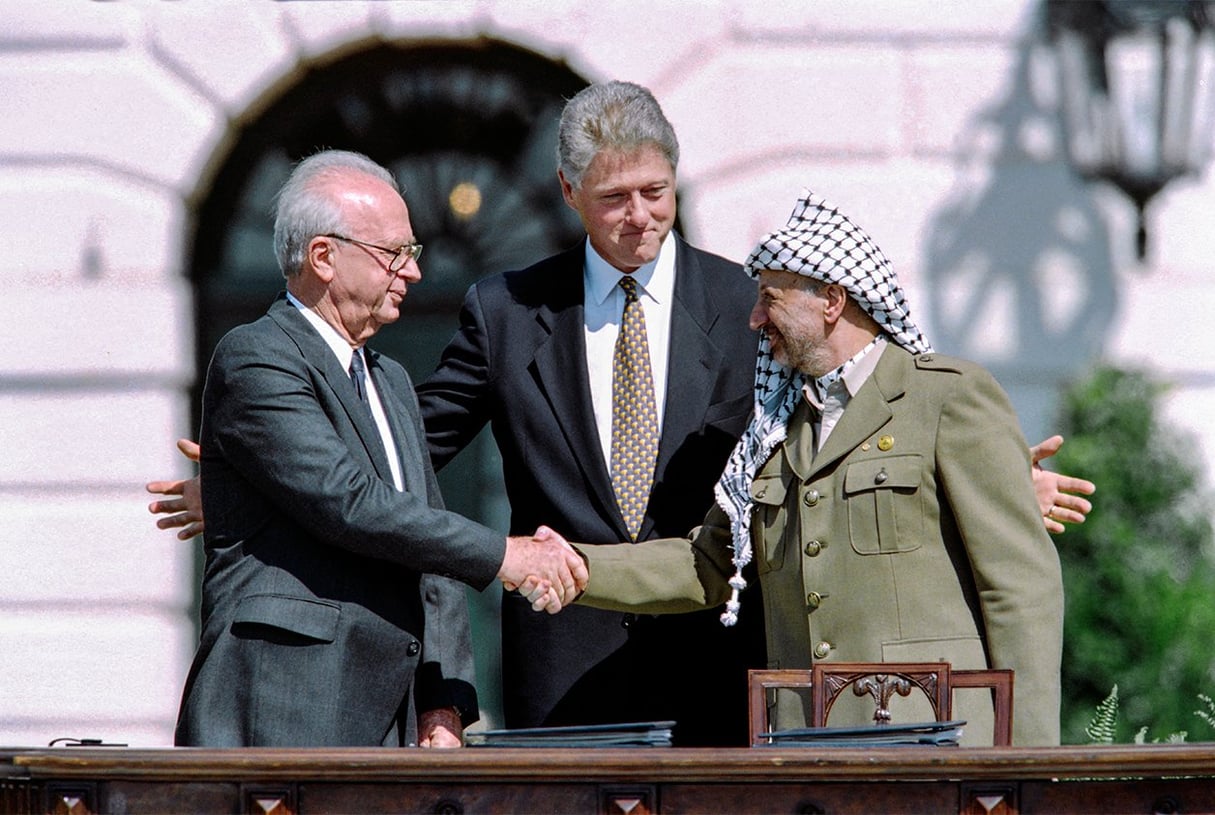 Le président américain Bill Clinton entre le chef de l’OLP Yasser Arafat et le Premier ministre israélien Yitzahk Rabin qui se serrent la main pour la première fois, le 13 septembre 1993 à la Maison Blanche. © J. DAVID AKE / AFP