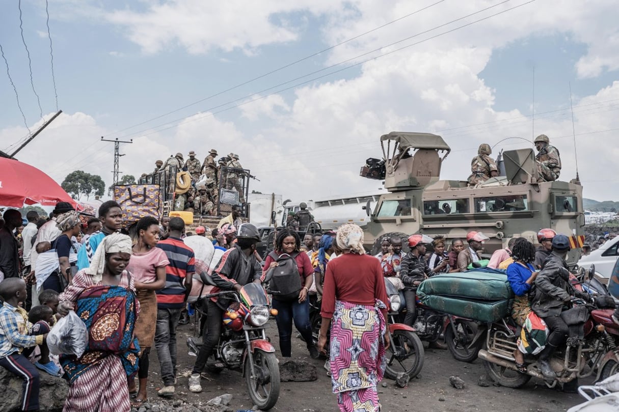 Des Congolais se rassemblent aux côtés de véhicules de l’armée sud-africaine, dont des soldats sont déployés dans le cadre de la mission de la Communauté de développement de l’Afrique australe (SADC),  près de Saké, le 7 février 2024. © Aubin Mukoni / AFP