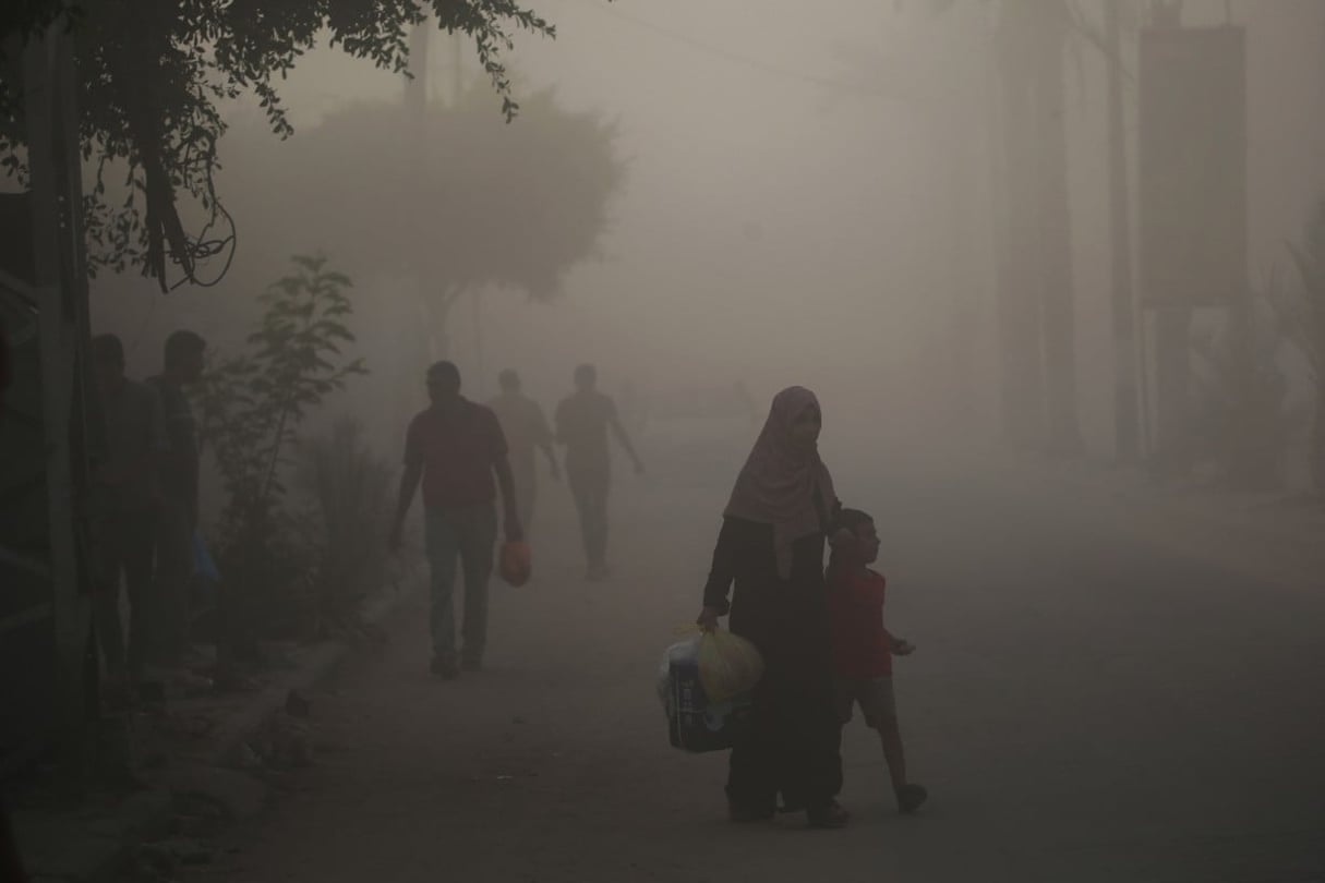 Des Palestiniens se frayent un chemin dans la poussière et la fumée après un bombardement dans le camp de réfugiés de Nousseirat, dans le centre de la bande de Gaza, le 22 août 2024. © Eyad BABA / AFP