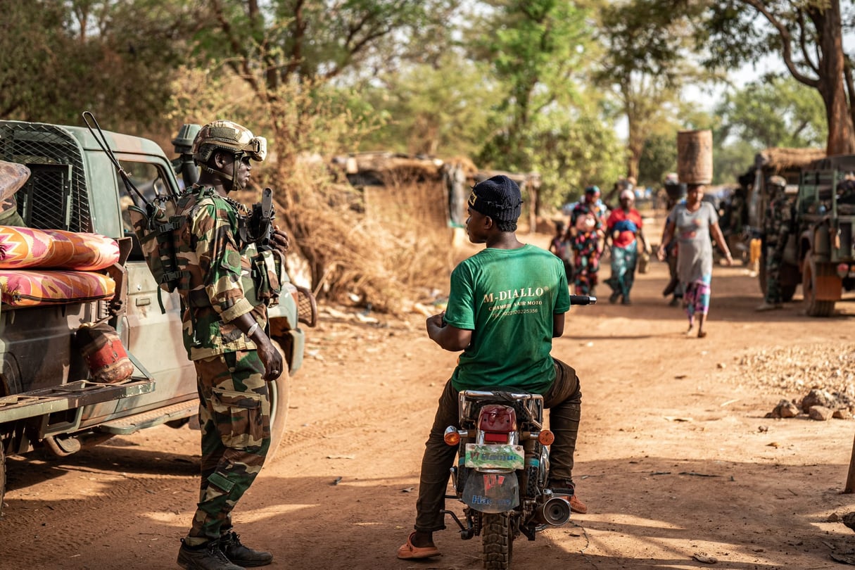 Un soldat sénégalais questionne un homme en moto, aux abords d’une mine d’or artisanale de la région de Kedougou, près du Mali, le 11 mai 2025. © AFP