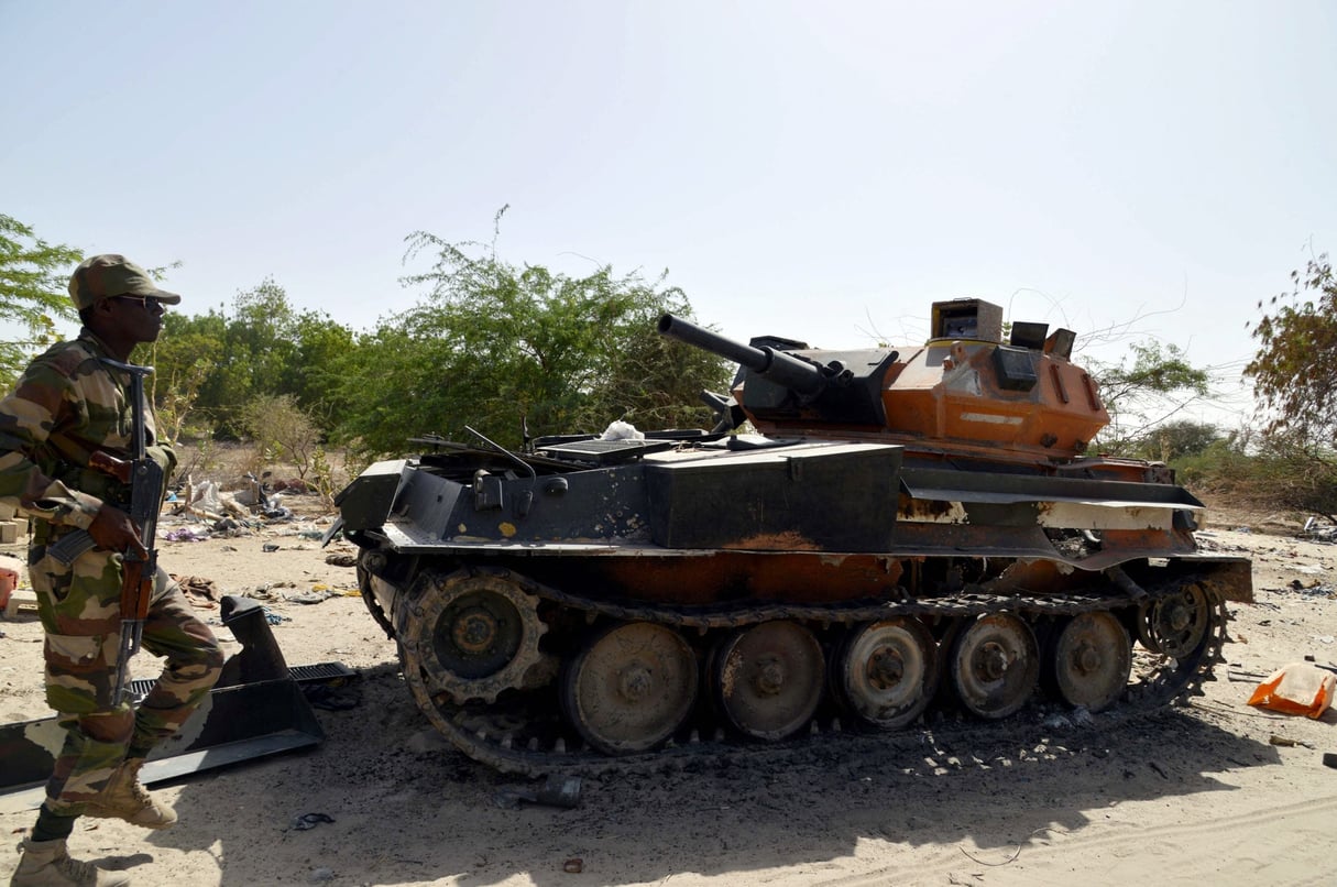 Un soldat de l'armée nigérienne s'approche d'un char calciné appartenant aux militants de Boko Haram, le 25 mai 2015 à Malam Fatori, dans le nord du Nigeria, près de la frontière avec le Niger. Les troupes nigériennes et tchadiennes y coopèrent avec les forces nigérianes pour combattre les islamistes de Boko Haram. Boko Haram, qui souhaite instaurer un État islamique rigoriste dans le nord-est du Nigeria, a été chassé des villes et territoires conquis, dont Malam Fatori, depuis février par les troupes nigérianes, appuyées par le Niger, le Tchad et le Cameroun. (Photo AFP / Issouf Sanogo)