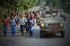 Des soldats français participant à l’opération Turquoise lors d’une patrouille en juin 1994, croisant des troupes hutues des forces gouvernementales rwandaises s’entraînant avec des bâtons, près de Gisenyie. © MONTAGE JA : Pascal GUYOT/AFP