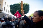 Un homme brandit du pain lors d’une manifestation devant le bureau du Premier ministre du gouvernement d’union nationale et éphémère président par intérim tunisien Mohamed Ghannouchi, le 23 janvier 2011, à Tunis. © MARTIN BUREAU/AFP
