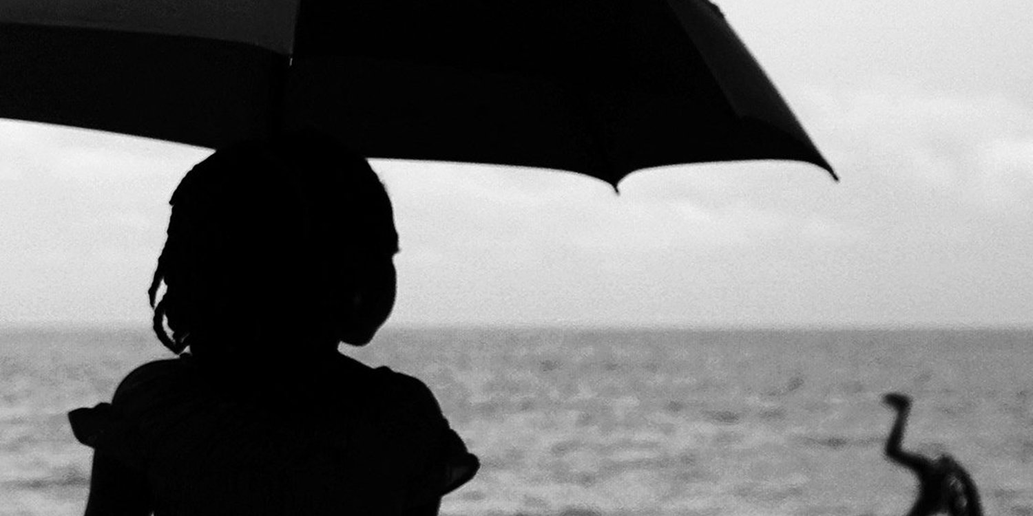 FBL-AFR-2017-FEATURE-BLACK AND WHITE A picture shows a girl holding an umbrella as a man somersaults at a beach in Libreville on the sidelines of the 2017 Africa Cup of Nations football tournament on January 15, 2017.
© GABRIEL BOUYS/AFP