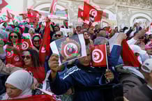 Des Tunisiens brandissent des pancartes lors d’un rassemblement de soutien au président Kaïs Saïed à Tunis, le 1er mai 2025. © Mohamed KHALIL / AFP