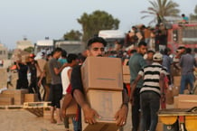 Des Palestiniens transportent des boîtes d’aide humanitaire près de Nuseirat dans le centre de la bande de Gaza, le 18 mai 2024. © Ali Hamad/APAIMAGES/SIPA