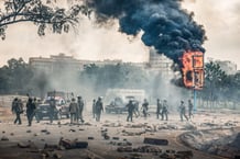 Des membres des forces de sécurité kényanes se rassemblent près d’un panneau d’affichage en feu dans le centre de Nairobi le 25 juin 2025, lors d’une journée de protestations prévue pour marquer le premier anniversaire de la prise d’assaut du Parlement.