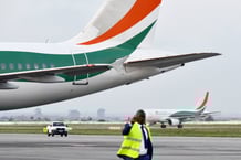 Un homme parle au téléphone à côté des avions de la compagnie aérienne nationale ivoirienne Air Côte d'Ivoire à l'aéroport Félix Houphouët-Boigny d'Abidjan le 18 juillet 2017.