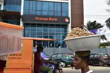 Des passants déambulent devant la banque Orange à Abidjan, en Côte d'Ivoire, le 24 juillet 2020. Le groupe de télécommunications Orange a annoncé le 23 juillet 2020 le lancement d'une banque mobile, Orange Bank Africa (OBA), en Côte d'Ivoire, et d'ici l'année suivante dans trois autres pays d'Afrique de l'Ouest, afin de « démocratiser l'accès aux services financiers ». Cette nouvelle banque 100 % numérique, filiale d'Orange (75 %) et de la banque ivoirienne NSIA (25 %), proposera à ses clients des microcrédits à partir de 5 000 francs CFA (7,50 euros) et un compte d'épargne rémunéré avec un dépôt minimum de 1 000 francs CFA, accessibles « en quelques secondes » depuis un téléphone mobile, selon Jean-Louis Menann-Kouamé, directeur général d'OBA. (Photo : Issouf SANOGO / AFP)