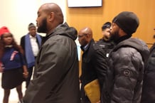 Charles Onana (au centre), encadré par son service de sécurité, à l’issue du délibéré au cours duquel il a été condamné pour contestation du crime de génocide des Tutsi, le 9 décembre 2024 à Paris. Il a fait appel. © Romain Chanson 