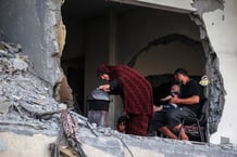 Une famille palestinienne se rassemble autour d’un poêle à bois de fortune dans un bâtiment endommagé à Khan Yunès, le 4 juillet 2024. © Bashar TALEB / AFP