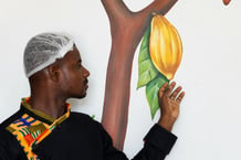 Devant une peinture d’une cabosse de cacao à Chocovi, la chocolaterie de Viviane Kouame, un artisan chocolatier ivoirien, à Abidjan, en Côte d’Ivoire, en mai 2024. © Luc Gnago / Reuters