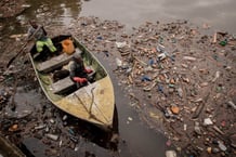 Deux ouvriers de la centrale hydroélectrique de Ruzizi I inspectent la rivière Ruzizi pour constater le niveau de déchets plastiques autour du barrage de la centrale à Bukavu, dans l'est de la République démocratique du Congo, le 17 mars 2022. À l'extrémité sud du lac Kivu, bordée de collines verdoyantes, une couche compacte de déchets plastiques se forme constamment, au point de bloquer les turbines de la plus grande centrale hydroélectrique de l'est de la République démocratique du Congo. Le barrage de Ruzizi attire comme un aimant les milliers de bouteilles, canettes et autres déchets jetés dans le lac, qui s'étend sur quelque 90 km à la frontière entre la RDC et le Rwanda.