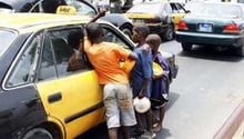 Des enfants « talibés » mendient à la fenêtre d’un taxi, dans une rue de Dakar. © AFP